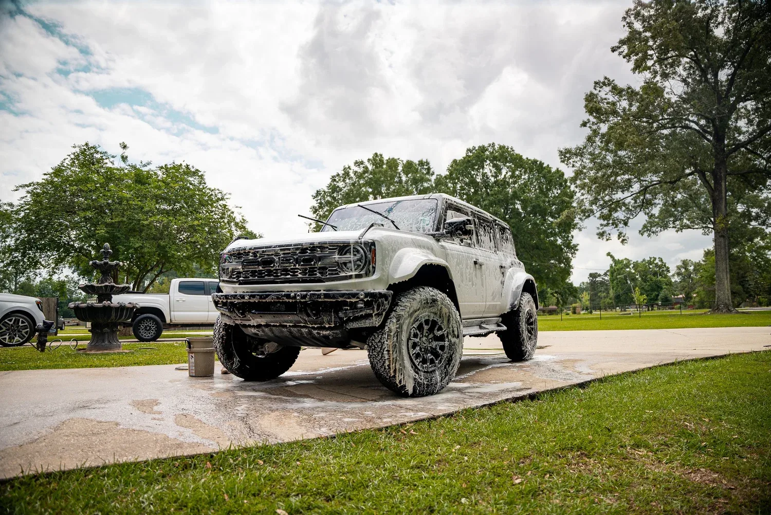 White off-road SUV covered in wash foam on a residential driveway