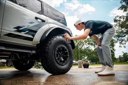 Detailer cleaning the wheel and tire of a white off-road SUV